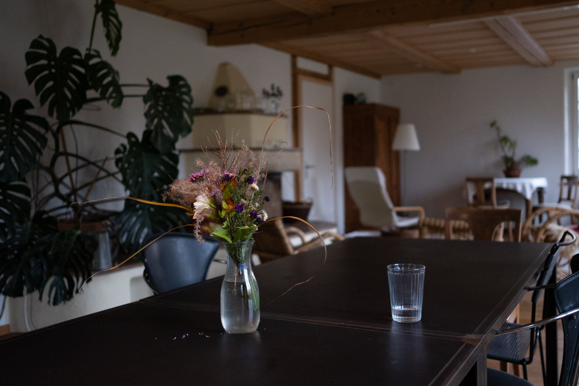 Ein bunter Strauss mit Gartenblumen steht auf einem schwarzen Tisch in einem gemütlich eingerichteten Wohnzimmer.